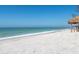 A beach with white sand, calm turquoise water, and a tiki hut on the beach at 1304 Casey Key Rd, Nokomis, FL 34275