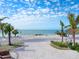 Driveway of a beach house leading to ocean with clear blue skies, palm trees, and well-maintained landscaping at 1304 Casey Key Rd, Nokomis, FL 34275