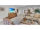 Bright living room with a tan sofa, wooden furniture, and a large flat screen television at 1465 Gulf Of Mexico Dr # 104, Longboat Key, FL 34228