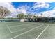Enjoy a match on this community tennis court with lush greenery and a view of beautiful homes under a bright, cloudy sky at 1465 Gulf Of Mexico Dr # 104, Longboat Key, FL 34228