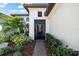 Elegant home entrance featuring a dark wood door, manicured garden beds, and mature palm trees at 1805 7Th St E, Palmetto, FL 34221
