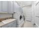 Laundry room has gray cabinets, white washer, dryer, sink, and white tile flooring at 1805 7Th St E, Palmetto, FL 34221