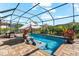 Backyard pool featuring a screened enclosure, lounge chairs in the water, an umbrella, and lush landscaping at 1805 7Th St E, Palmetto, FL 34221