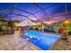 Backyard pool featuring a screened enclosure, lounge chairs in the water, and an umbrella at dusk at 1805 7Th St E, Palmetto, FL 34221