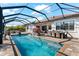 A sparkling screened-in pool with an outdoor dining table, lush plants, and a covered seating area at 1805 7Th St E, Palmetto, FL 34221