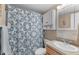 Well-lit bathroom features a shower with patterned curtain, vanity, and storage cabinet at 1807 Sunny Dr # E4, Bradenton, FL 34207