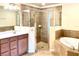 Elegant bathroom featuring tiled shower, soaking tub, and wooden vanity with solid surface counter at 20080 Ragazza Cir # 102, Venice, FL 34293