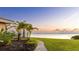 Well-manicured backyard landscaping with pavers and tropical palm trees with a distant water view at sunset at 202 Gaines Ave, Sarasota, FL 34243