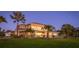 Evening shot of the home's exterior with lush landscaping, a sprawling lawn, and mature palm trees at 202 Gaines Ave, Sarasota, FL 34243