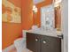 Stylish powder room with designer vanity, fixtures, and bright orange accent wall at 212 Haverkos Ct, Holmes Beach, FL 34217