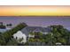 Expansive waterfront home with lush tropical landscaping and serene water views, bathed in the warm glow of sunset at 212 Haverkos Ct, Holmes Beach, FL 34217