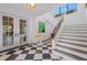 Bright foyer features a black and white checkered floor, staircase, and french doors, offering a grand entrance at 212 Haverkos Ct, Holmes Beach, FL 34217
