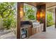 Stylish outdoor kitchen with a built-in grill, mini-fridge, wood cabinets, and well-lit ambiance for outdoor cooking at 212 Haverkos Ct, Holmes Beach, FL 34217