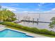 Waterfront view from pool featuring a wooden pier extending into the calm water with lush greenery in the foreground at 212 Haverkos Ct, Holmes Beach, FL 34217
