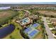 Expansive aerial view showcasing community pool, tennis courts, and lush surroundings, highlighting a vibrant neighborhood at 220 Cassano Dr, Nokomis, FL 34275
