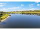 A scenic shot of the expansive lake with lush greenery, trees, and blue skies in the background at 220 Cassano Dr, Nokomis, FL 34275