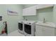 Well-lit laundry room featuring white cabinets, modern washer and dryer, and a sink with a sleek faucet at 220 Cassano Dr, Nokomis, FL 34275