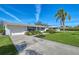 View of the front exterior of the property with a garage, landscaped lawn, and palm trees at 2406 Breakwater Cir, Sarasota, FL 34231