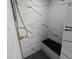 Modern bathroom shower featuring marble-like tile and a sleek black shower seat for a spa-like experience at 3507 65Th Avenue E Cir, Sarasota, FL 34243