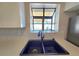 Close up of kitchen sink under a window that looks out to the backyard and covered patio at 3507 65Th Avenue E Cir, Sarasota, FL 34243