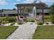 Inviting outdoor seating area with pergola, fountain, and white stone pathway, perfect for relaxation and enjoying the serene surroundings at 3507 65Th Avenue E Cir, Sarasota, FL 34243