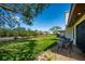 A view of the backyard with chairs on a patio overlooking the lawn, canal and trees at 3641 Gleneagle Dr # 12D, Sarasota, FL 34238