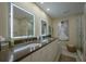 Elegant bathroom with double sinks, vanity with stone countertops, backlit mirrors, and a modern glass shower at 3641 Gleneagle Dr # 12D, Sarasota, FL 34238