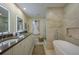 Luxurious bathroom featuring double sinks, vanity with stone counters, soaking tub, and glass enclosed shower at 3641 Gleneagle Dr # 12D, Sarasota, FL 34238