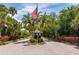 Guarded entrance gate with an American flag surrounded by palm trees and manicured landscaping at 3641 Gleneagle Dr # 12D, Sarasota, FL 34238