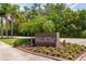 Community entrance sign surrounded by vibrant flower beds and lush tropical plants at 3641 Gleneagle Dr # 12D, Sarasota, FL 34238