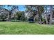 Sprawling backyard with lush green lawn, mature trees, trampoline, and outdoor seating area at 4045 Lisbon Pl, Sarasota, FL 34231