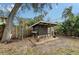 Backyard chicken coop featuring a dark exterior, sheltered run, and charming details like a windmill and potted plants at 4045 Lisbon Pl, Sarasota, FL 34231