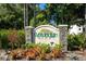 Woodridge Oaks community sign with lush greenery, landscaping, and a glimpse of a home in the background at 4255 67Th Avenue E Cir, Sarasota, FL 34243