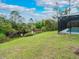 The house has a spacious backyard with green grass and natural vegetation, offering privacy and space at 4486 Shrimp Ln, North Port, FL 34286