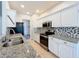 Galley kitchen featuring granite countertops, stainless steel appliances, white cabinetry, and modern mosaic backsplash at 4744 105Th E Ave, Parrish, FL 34219