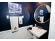 Elegant powder room featuring blue walls, white wainscoting, and a stylish round mirror at 5118 78Th St E Cir, Bradenton, FL 34203