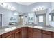 Bathroom with dual sinks, wood cabinets, granite counters, and spacious mirrors at 5119 Admiral Pointe Dr, Apollo Beach, FL 33572