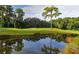 Scenic view of a lush green golf course with a pond reflecting the surrounding trees and sky at 5655 Downham Mdws, Sarasota, FL 34235