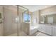 Bright bathroom with a glass-enclosed shower, soaking tub, double vanity, and a scenic window view at 5715 Woodland Sage Dr, Sarasota, FL 34238