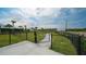 Community dog park entrance gate with green grass, trees, a sidewalk and a black fence at 5715 Woodland Sage Dr, Sarasota, FL 34238