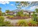 Exterior view of a landscaped backyard with a screened-in lanai, gravel paths, and lush tropical foliage at 6105 55Th Avenue E Cir, Bradenton, FL 34203