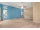 Carpeted living room with a ceiling fan, light-colored walls and two windows at 6105 55Th Avenue E Cir, Bradenton, FL 34203