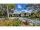 Charming single-story home with a lush front yard, a paved driveway, and a metal roof at 614 Tropical Cir, Sarasota, FL 34242