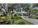 Charming single-story home with lush landscaping and a brick paved driveway in a tropical setting at 614 Tropical Cir, Sarasota, FL 34242