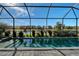 Screened-in pool overlooking a serene lake, surrounded by landscaped greenery and blue skies at 6378 Grandview Hill Ct, Bradenton, FL 34203