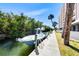 Picturesque waterfront view with a boat docked alongside lush greenery and high-rise condo, and palm trees at 6415 Midnight Pass Rd # 904, Sarasota, FL 34242