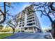 Stunning condo building exterior featuring multiple balconies and beautiful landscaping against a blue sky at 6415 Midnight Pass Rd # 904, Sarasota, FL 34242