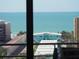 Scenic ocean view through the window showing adjacent buildings and palm trees at 6415 Midnight Pass Rd # 904, Sarasota, FL 34242
