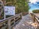 Wooden boardwalk leading to the beach, passing a 'Share the Shore' information sign among lush greenery at 660 Fox St, Longboat Key, FL 34228