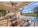 An inviting outdoor kitchen with a built-in grill, beverage cooler, and comfortable seating overlooking the pool and water at 7108 Callander Cv, Lakewood Ranch, FL 34202
